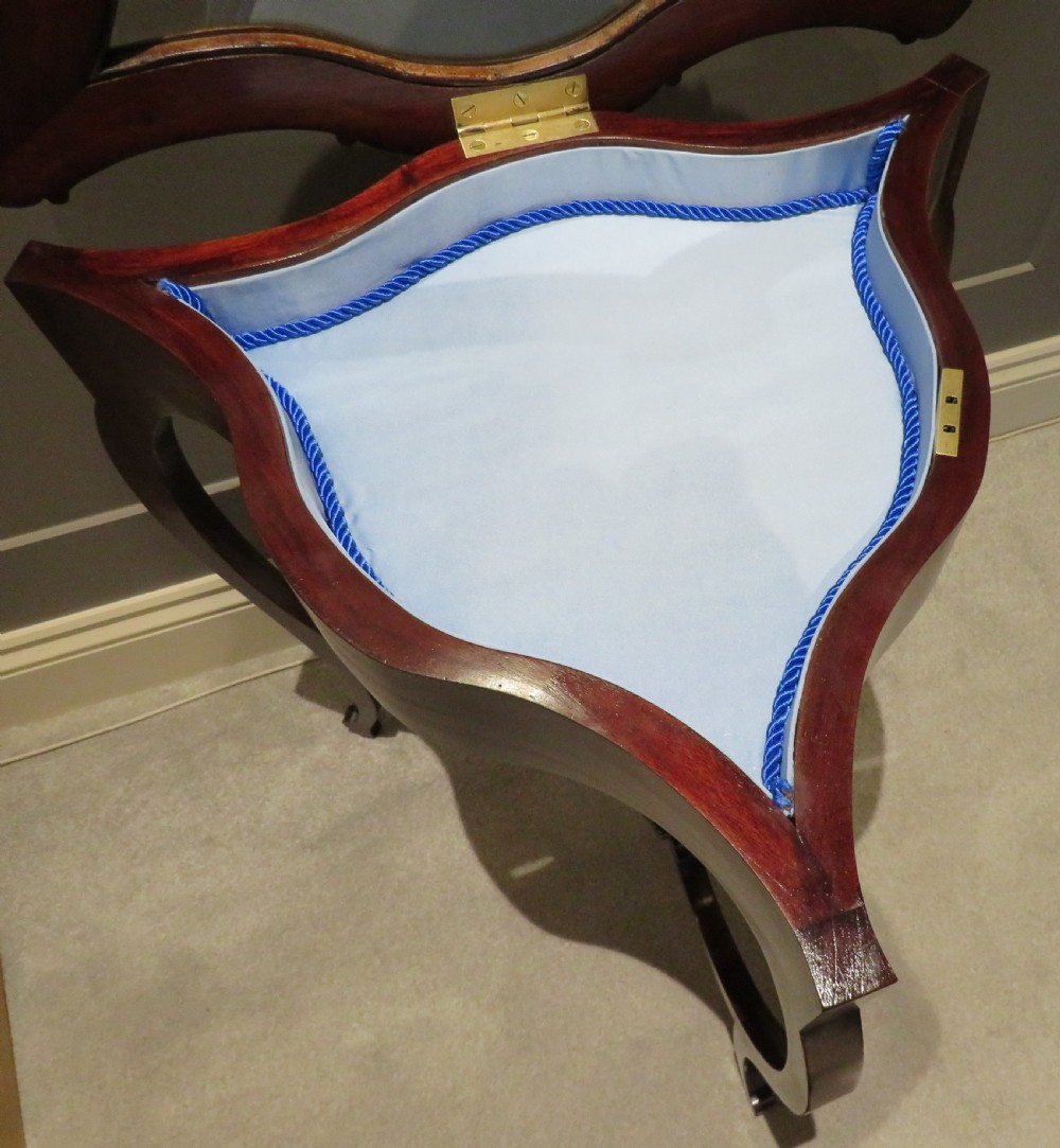 An Edwardian clover-shaped mahogany bijouterie table featuring a hinged glazed top, blue fabric lining, lower shelf, and cabriole legs. View II