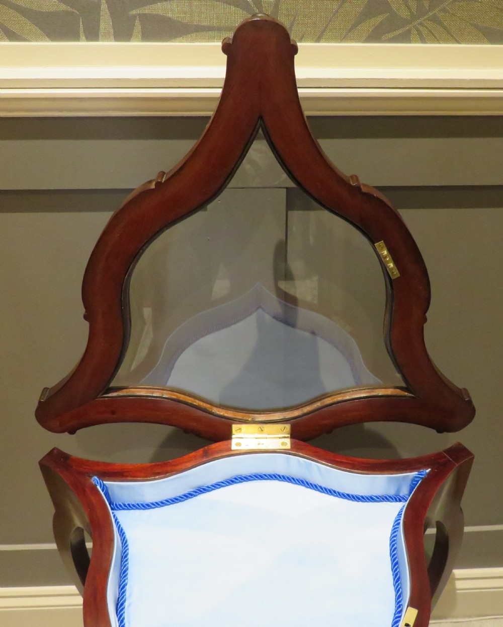 An Edwardian clover-shaped mahogany bijouterie table featuring a hinged glazed top, blue fabric lining, lower shelf, and cabriole legs. View IV