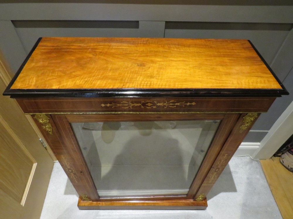 A Victorian walnut pier cabinet featuring a single glazed door, floral marquetry inlay, and gilt brass corner mounts. View II