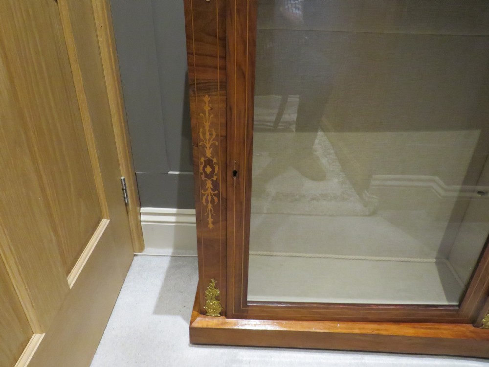 A Victorian walnut pier cabinet featuring a single glazed door, floral marquetry inlay, and gilt brass corner mounts. View IV