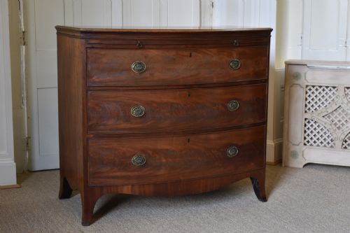 fig 1. A Georgian flame mahogany bow-front chest of drawers with three open graduated drawers and circular brass handles.