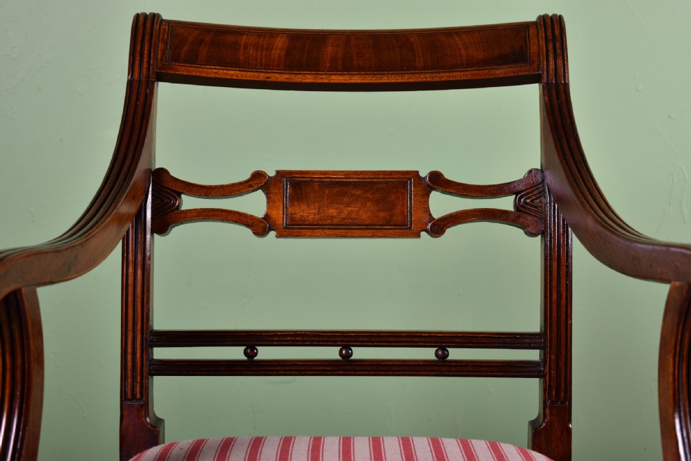 A pair of antique Scottish Regency mahogany armchairs featuring scrolled arms, turned front legs, and pink striped fabric seat cushions. View II