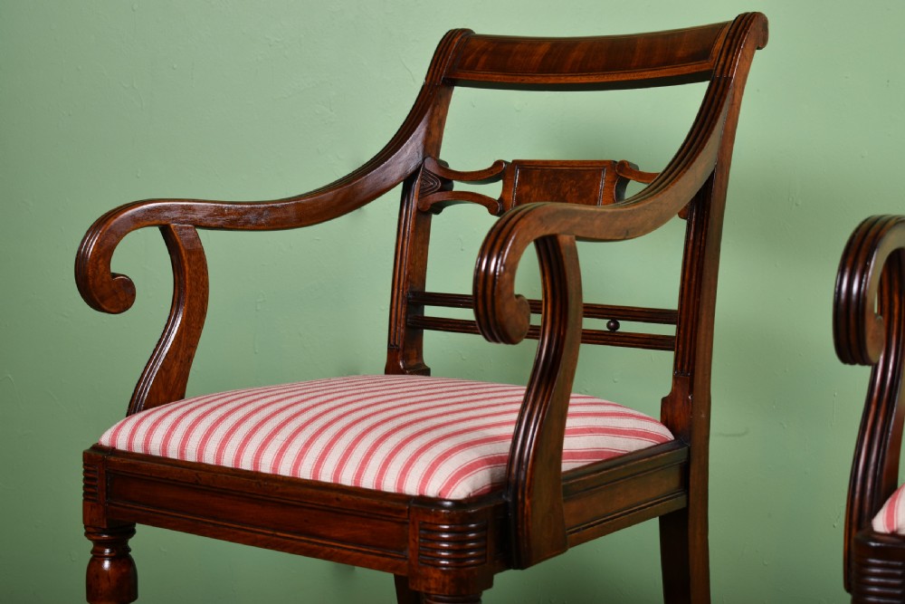 A pair of antique Scottish Regency mahogany armchairs featuring scrolled arms, turned front legs, and pink striped fabric seat cushions. View IV