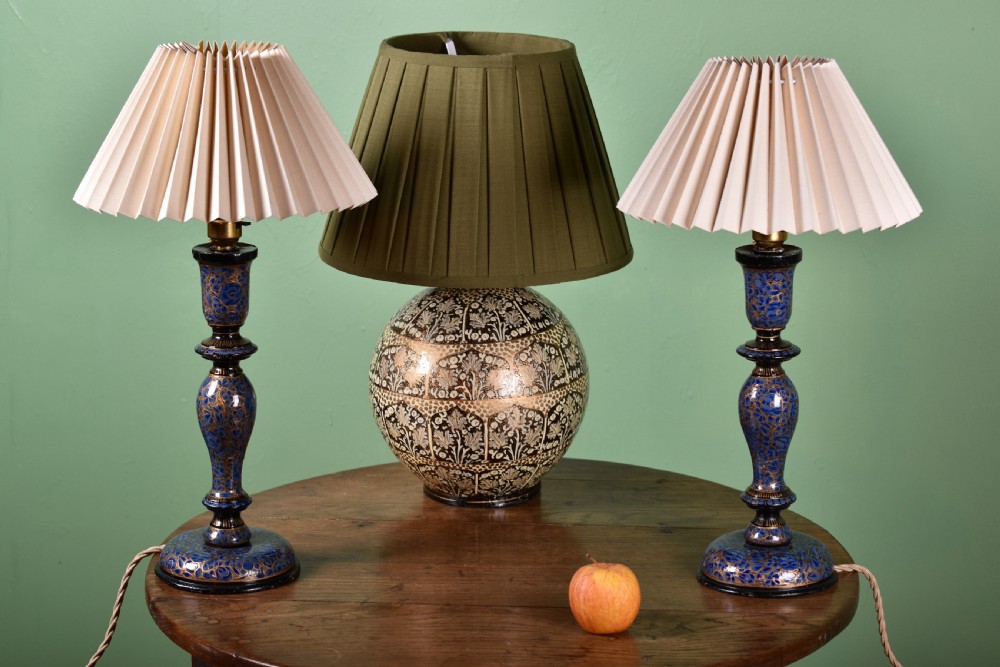 Three hand-painted Kashmiri table lamps consisting of two blue baluster stems and one central spherical patterned base, each topped with pleated lampshades.