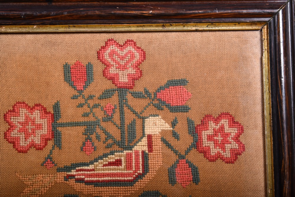 An 1844 Victorian needlework sampler framed in dark wood featuring a central bird, red flowers, two hearts, and hand-stitched lettering. View II