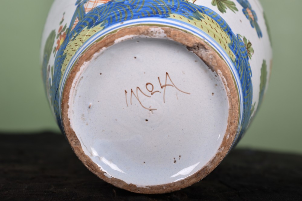 A white tin-glazed earthenware vase featuring hand-painted polychrome Garofano carnation motifs in orange, green, blue, and purple. View V
