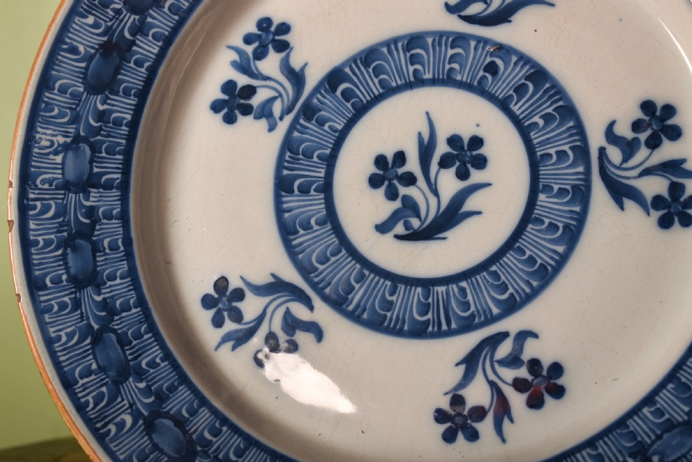A circular antique blue and white tin-glazed earthenware shallow bowl decorated with hand-painted floral sprigs and concentric patterned borders. View II