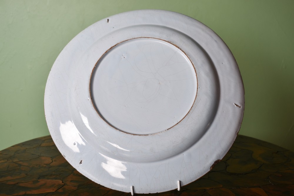 A circular antique blue and white tin-glazed earthenware shallow bowl decorated with hand-painted floral sprigs and concentric patterned borders. View IV