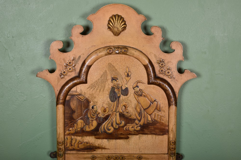 A tall, narrow cream painted wall mirror featuring a shaped scroll crest with a central shell motif and a hand-painted chinoiserie scene above the rectangular glass. View II