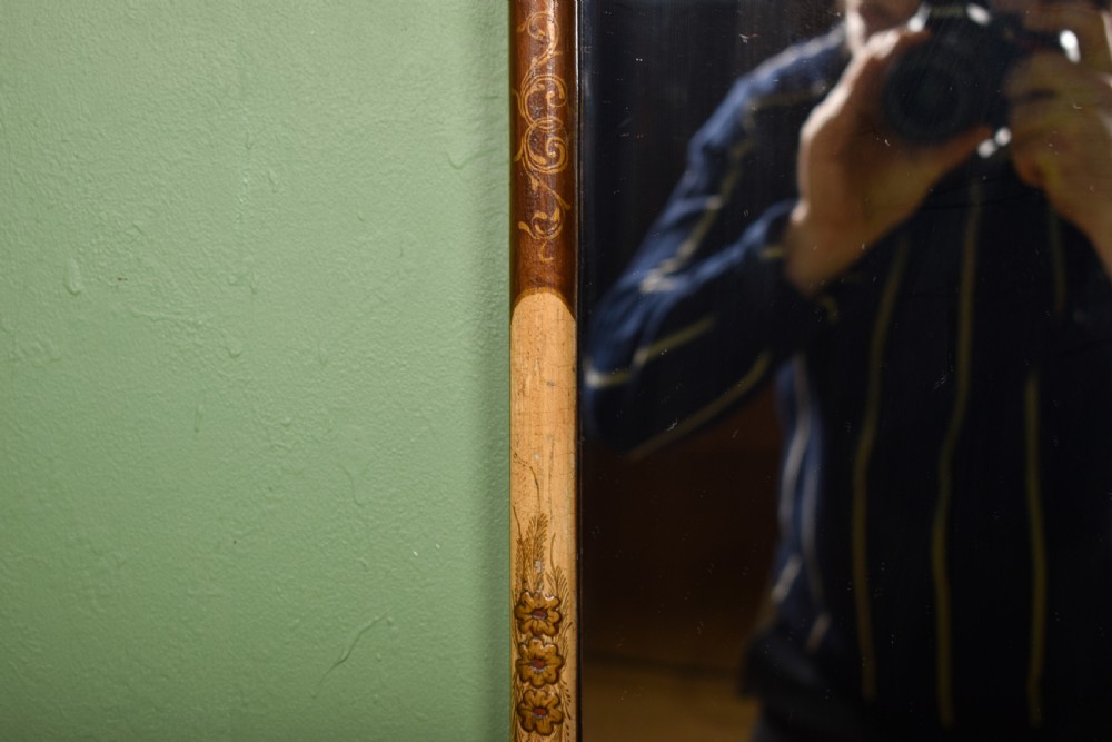 A tall, narrow cream painted wall mirror featuring a shaped scroll crest with a central shell motif and a hand-painted chinoiserie scene above the rectangular glass. View IV