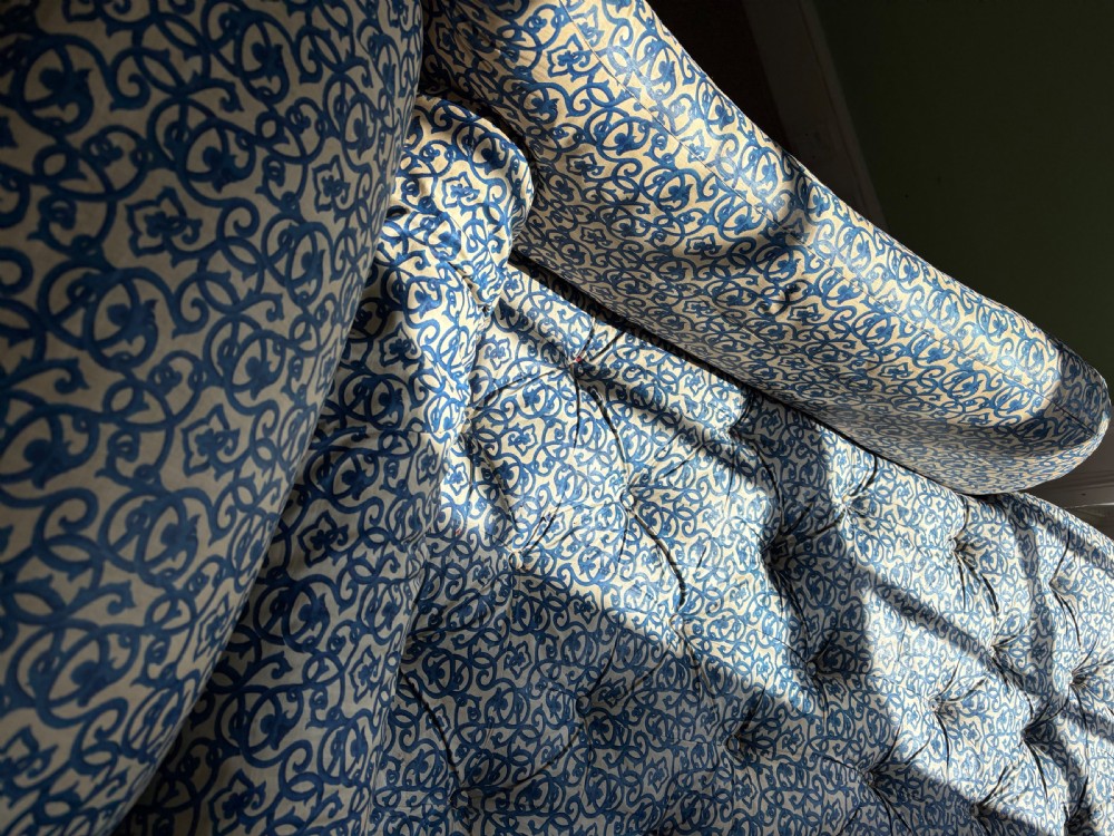 A Victorian upholstered chaise longue featuring a blue and white patterned fabric, a matching bolster cushion, and turned dark wood legs on brass castors. View III