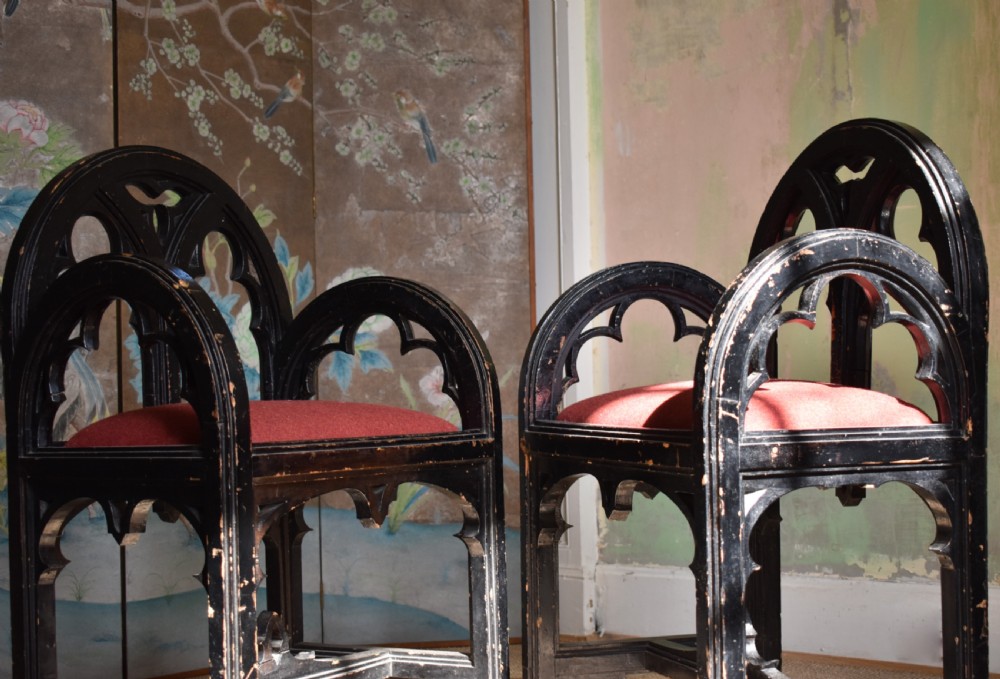 A pair of distressed black painted Gothic Revival armchairs featuring carved lancet tracery cutouts and red upholstered seats. View II