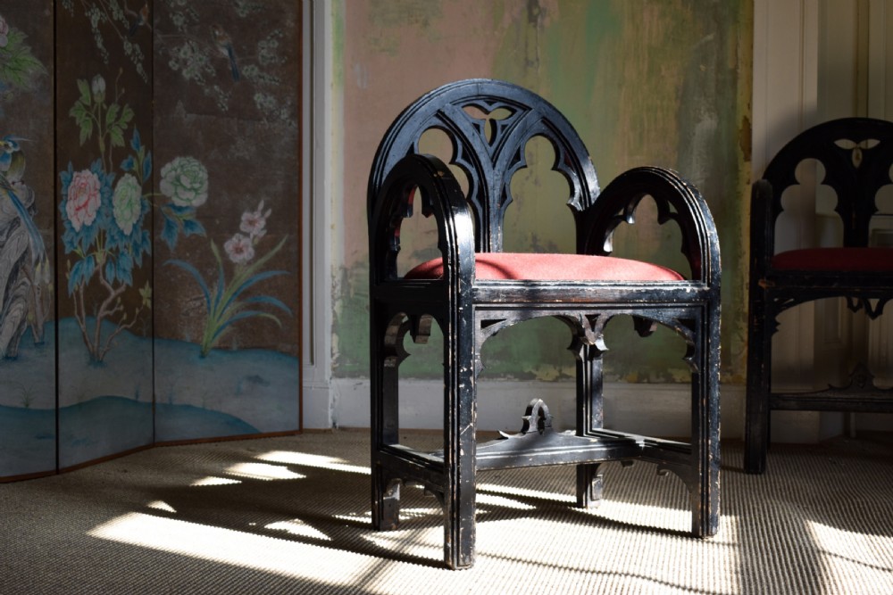A pair of distressed black painted Gothic Revival armchairs featuring carved lancet tracery cutouts and red upholstered seats. View III