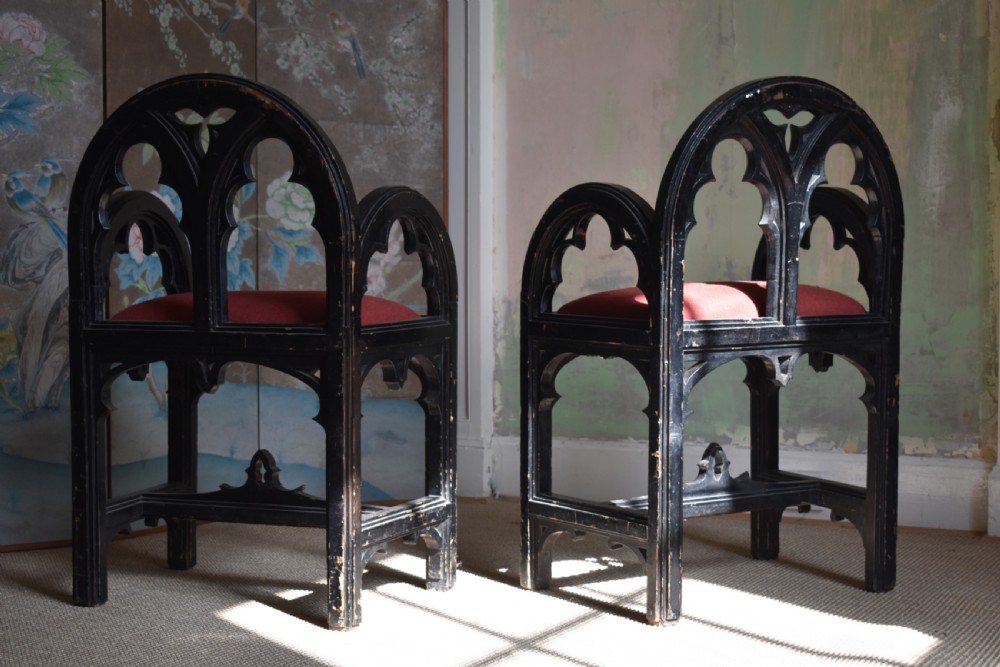 A pair of distressed black painted Gothic Revival armchairs featuring carved lancet tracery cutouts and red upholstered seats. View IV