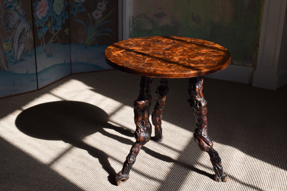 A circular dark wood side table supported by three gnarled and twisted natural grapevine legs.