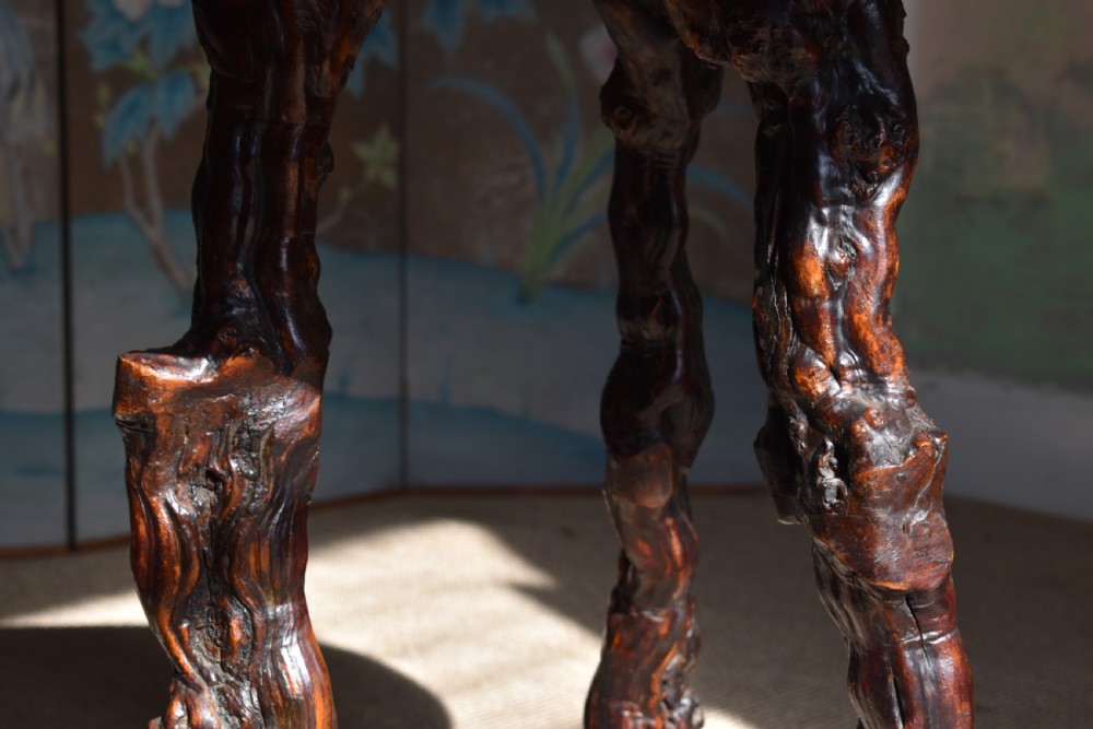 A circular dark wood side table supported by three gnarled and twisted natural grapevine legs. View III