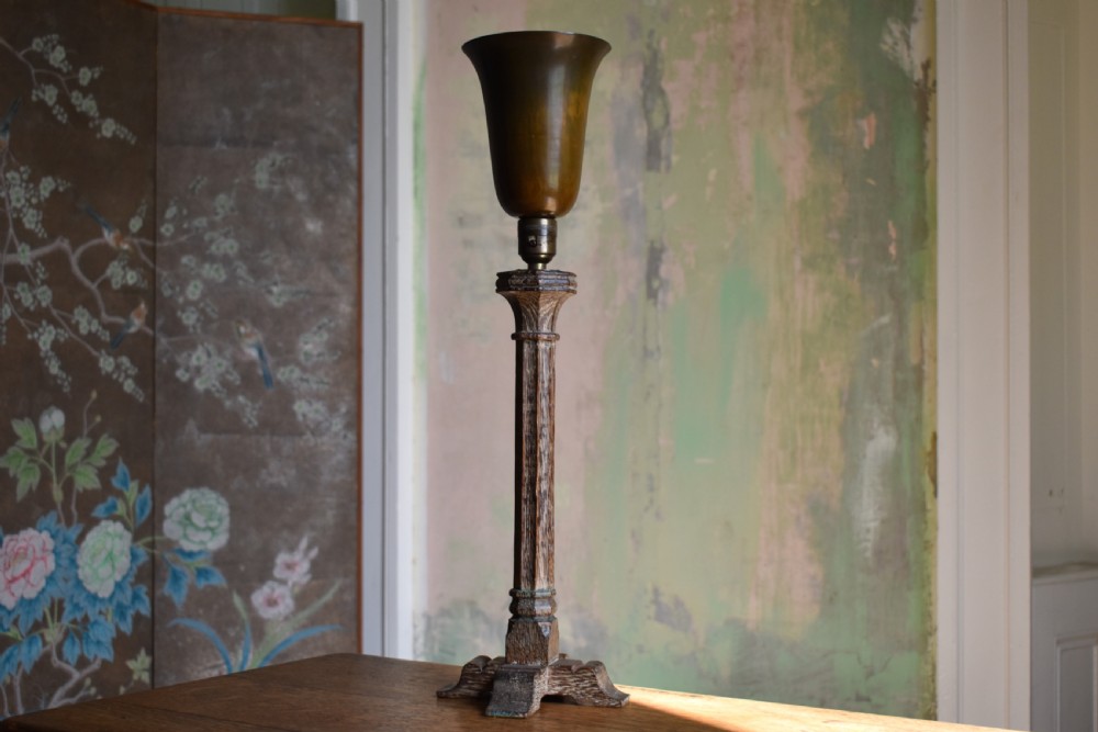 A tall limed oak table lamp base featuring a fluted column, stepped pedestal base, and a flared brass fitting.