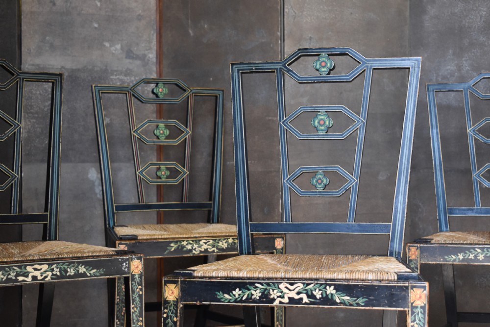 A set of four George III black-painted side chairs featuring geometric lattice backs with painted medallions, floral apron details, and woven rush seats. View II