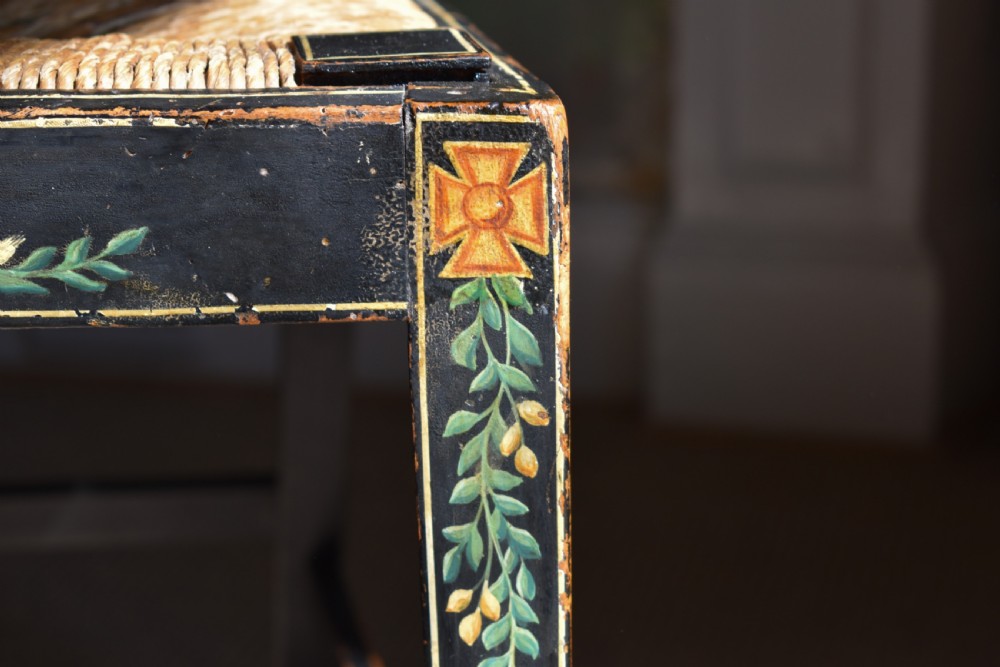 A set of four George III black-painted side chairs featuring geometric lattice backs with painted medallions, floral apron details, and woven rush seats. View III