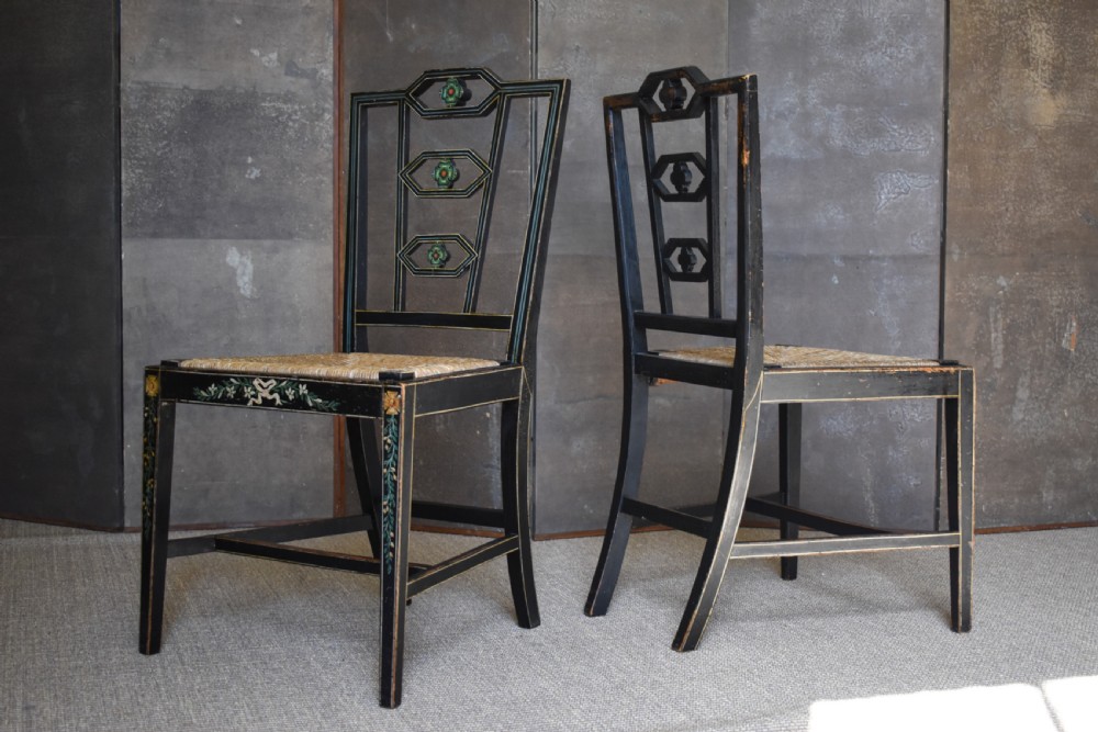 A set of four George III black-painted side chairs featuring geometric lattice backs with painted medallions, floral apron details, and woven rush seats. View V