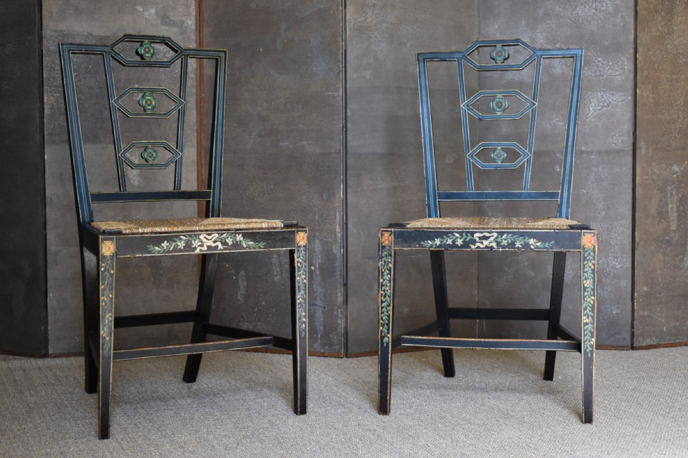 A set of four George III black-painted side chairs featuring geometric lattice backs with painted medallions, floral apron details, and woven rush seats. View VI
