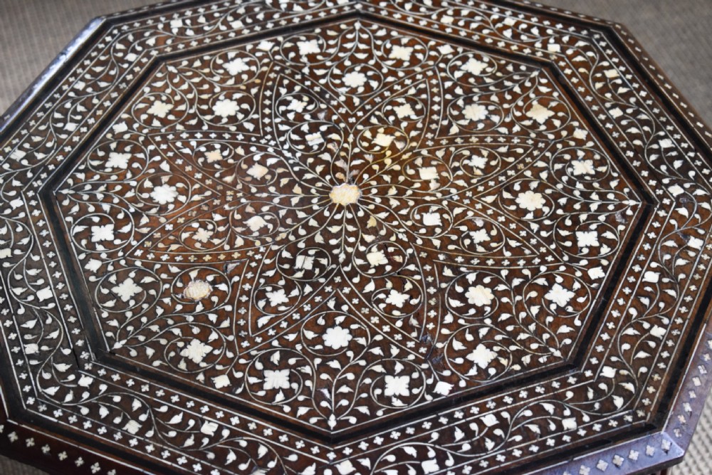 An octagonal dark wood side table featuring intricate bone inlay floral pattern work and decorative arched aprons. View V