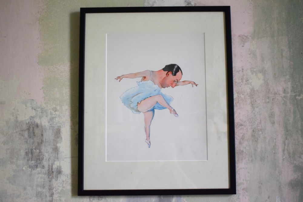A framed original watercolour illustration depicting a humorous male figure in a light blue ballet tutu and pointe shoes performing a pose.