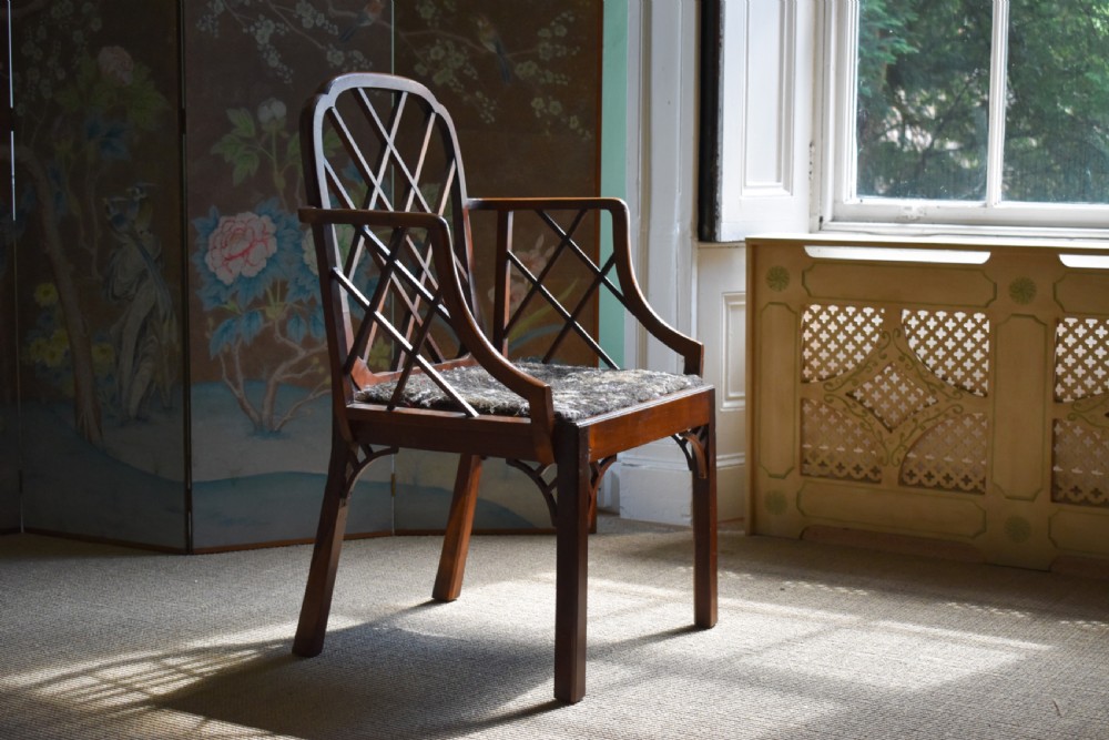 A George III mahogany Cockpen armchair featuring a lattice fretwork backrest, open arms, and a patterned upholstered seat cushion.