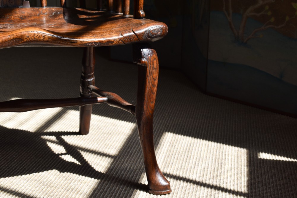 A George III wooden Windsor armchair featuring a shaped saddle seat, comb back rest with splat, and cabriole front legs. View III