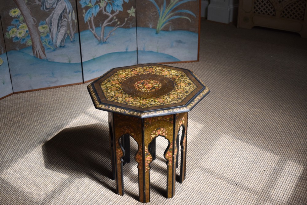 An octagonal Indian Kashmiri side table featuring intricate hand-painted floral motifs in gold, red, and green on a dark lacquered ground, resting alongside its matching folding arch-shaped base. View IV