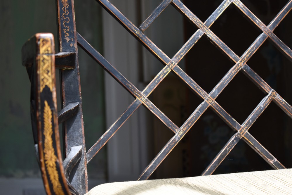 An antique ebonised Chinoiserie Cockpen armchair featuring a dark geometric lattice backrest, fretwork arm supports, straight legs, and a light-coloured fabric seat. View II