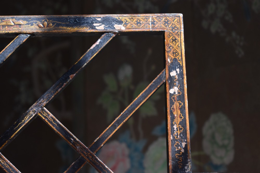 An antique ebonised Chinoiserie Cockpen armchair featuring a dark geometric lattice backrest, fretwork arm supports, straight legs, and a light-coloured fabric seat. View V