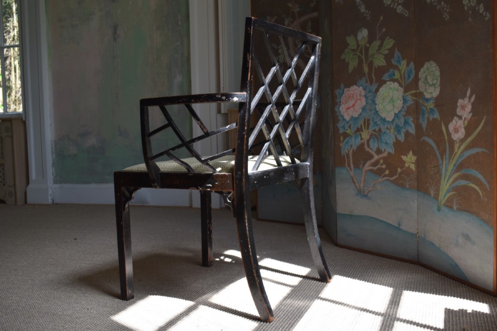 An antique ebonised Chinoiserie Cockpen armchair featuring a dark geometric lattice backrest, fretwork arm supports, straight legs, and a light-coloured fabric seat. View VI