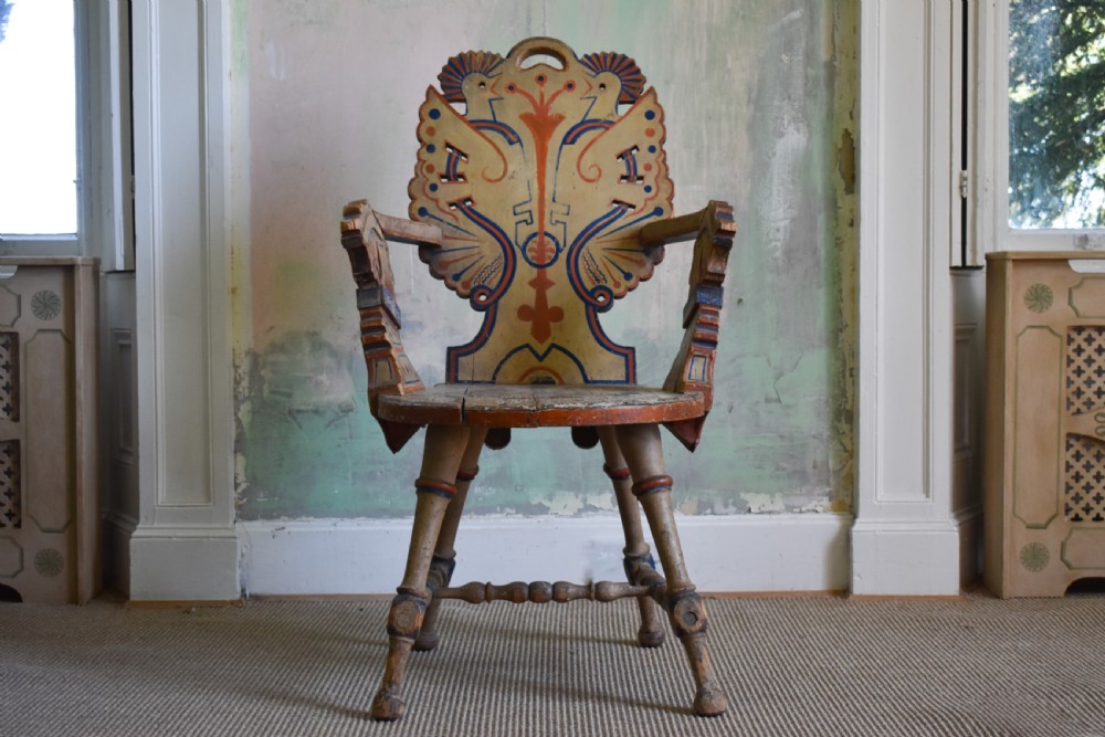 A Swedish folk art wooden armchair with a carved backrest featuring yellow, red, and blue painted details.