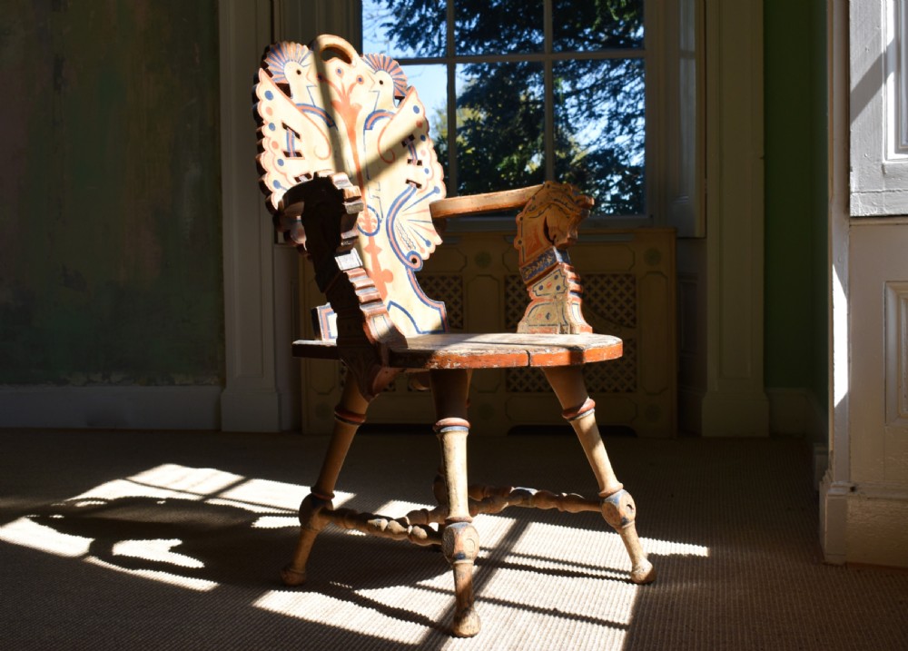 A Swedish folk art wooden armchair with a carved backrest featuring yellow, red, and blue painted details. View III