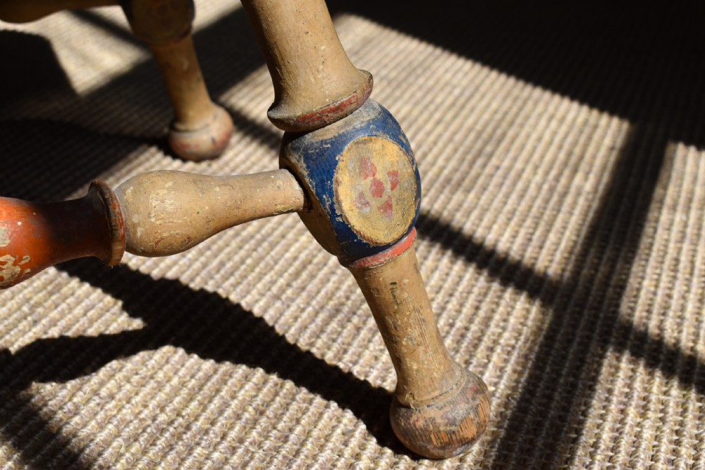 A Swedish folk art wooden armchair with a carved backrest featuring yellow, red, and blue painted details. View VI