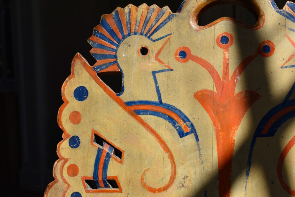A Swedish folk art wooden armchair with a carved backrest featuring yellow, red, and blue painted details. View VII