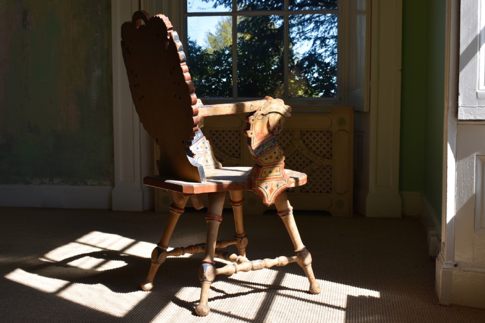 A Swedish folk art wooden armchair with a carved backrest featuring yellow, red, and blue painted details. View IX