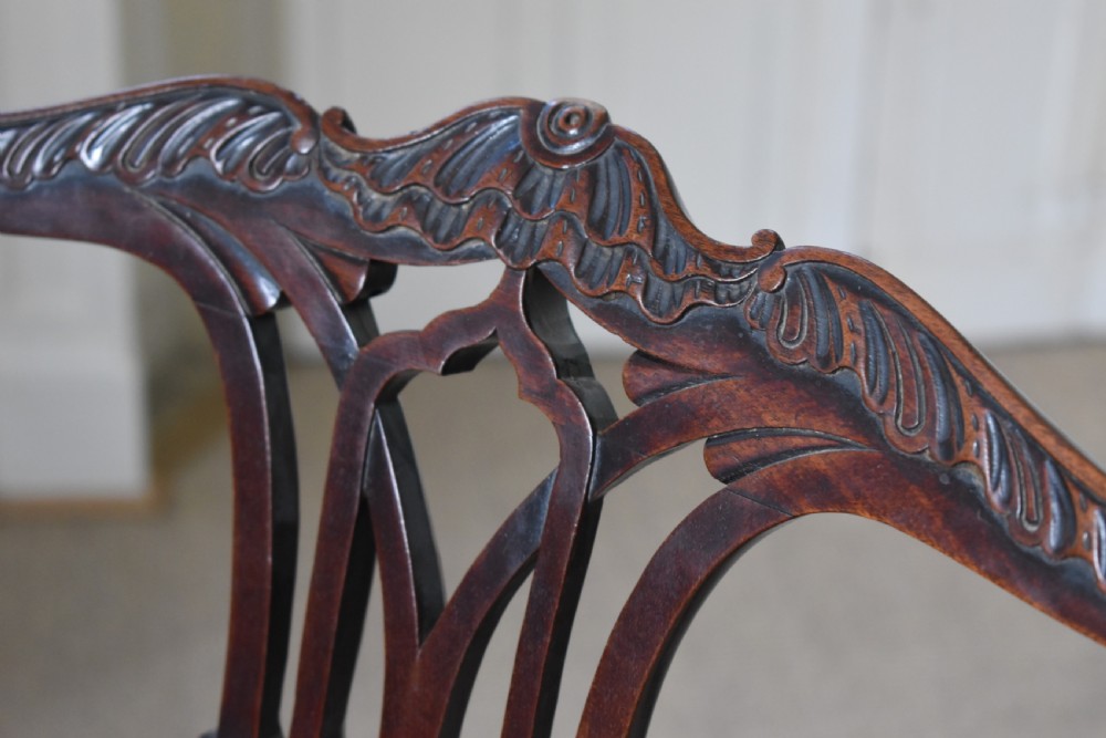 A pair of dark mahogany side chairs with intricate pierced back splats, carved square legs with fretwork, and tapestry fabric seats. View V