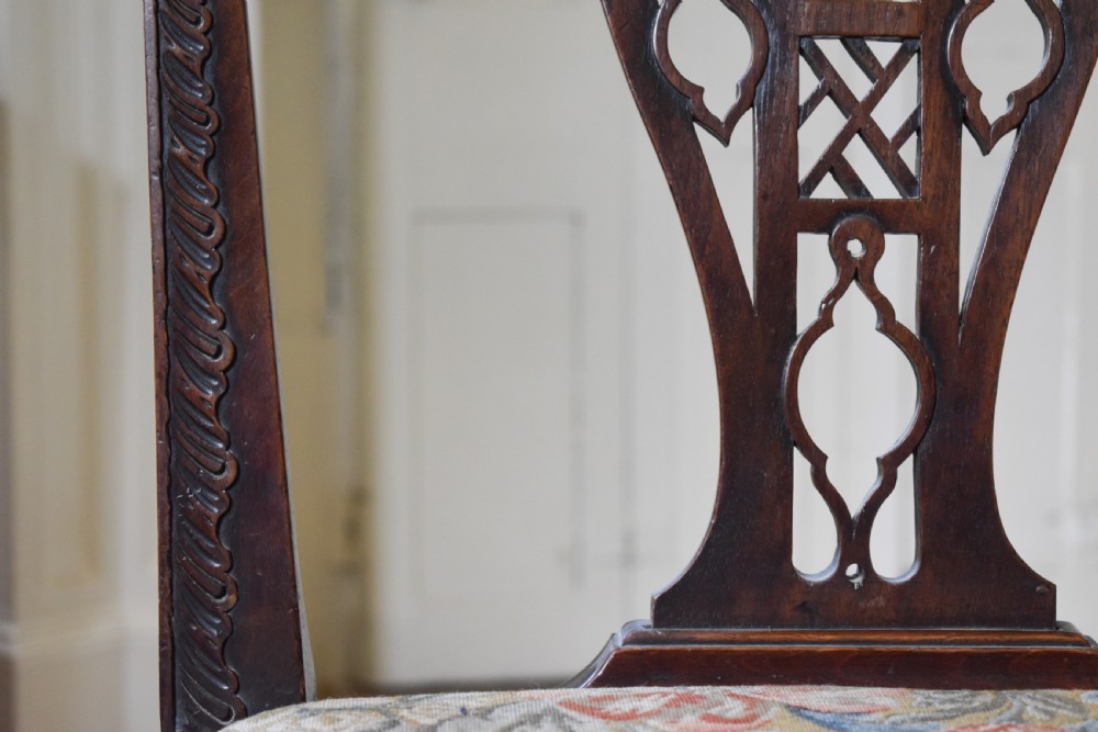 A pair of dark mahogany side chairs with intricate pierced back splats, carved square legs with fretwork, and tapestry fabric seats. View VI