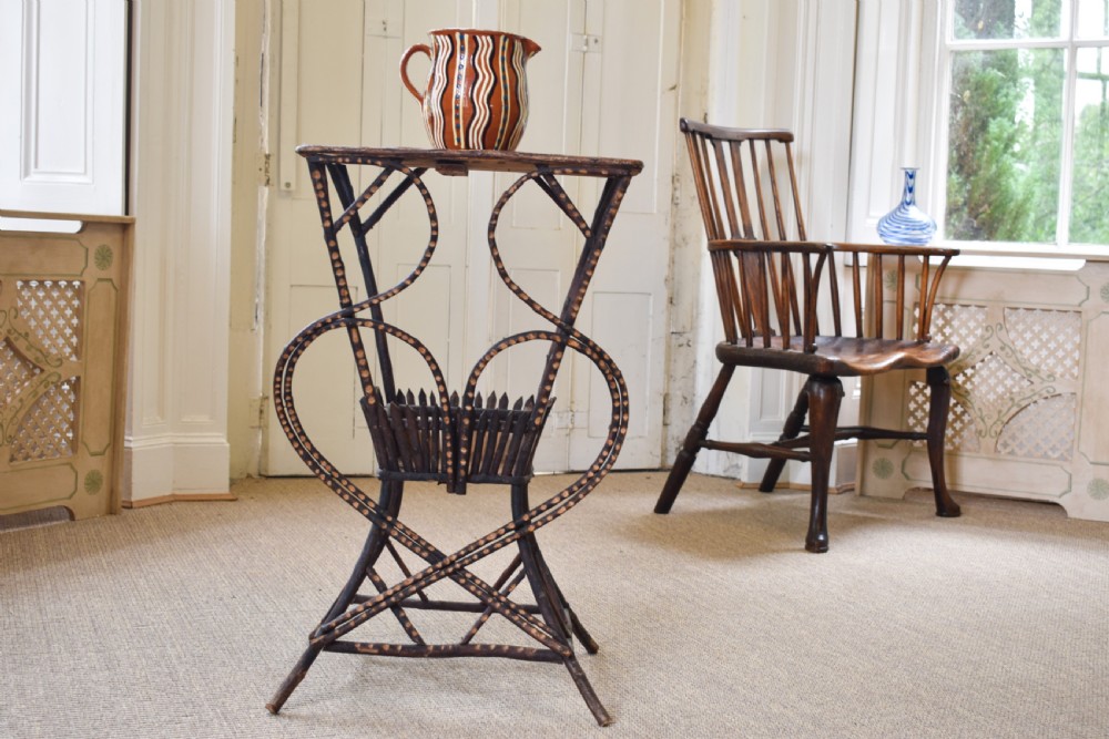 An antique folk art side table crafted from dark bent twigs with decorative notched patterns and arched bracing. View V