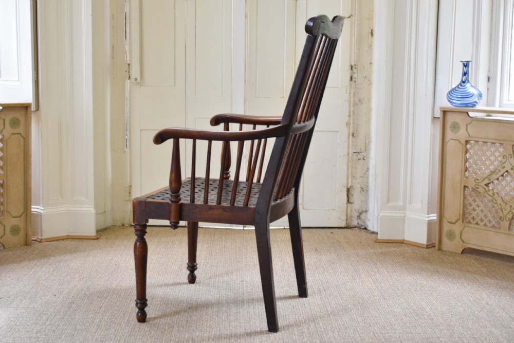 A dark timber country armchair featuring a tall spindle backrest, flat armrests on turned supports, a woven seat, and turned front legs. View II