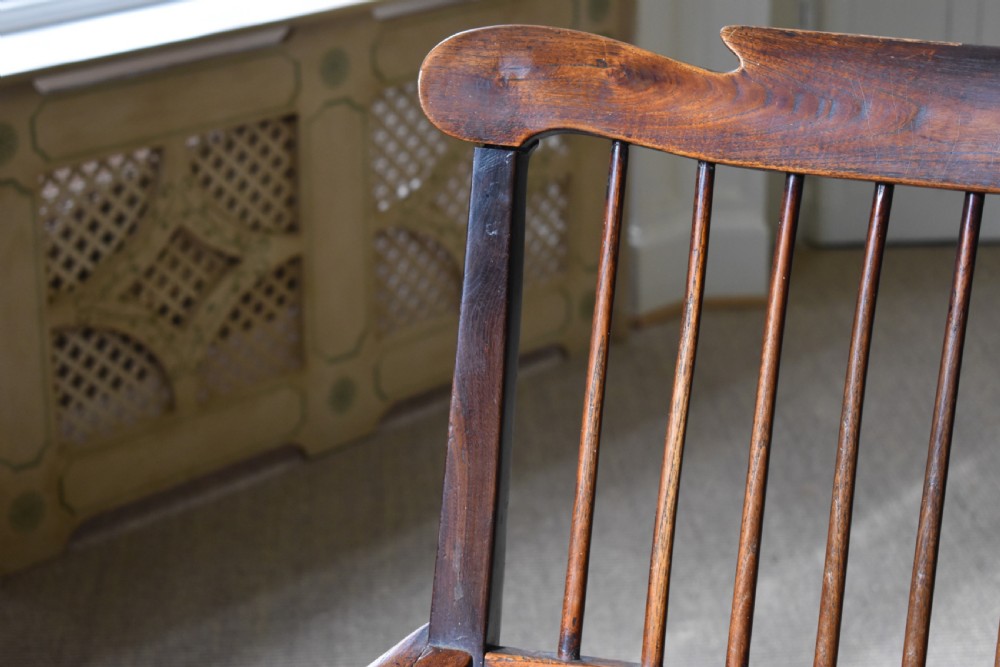 A dark timber country armchair featuring a tall spindle backrest, flat armrests on turned supports, a woven seat, and turned front legs. View IV