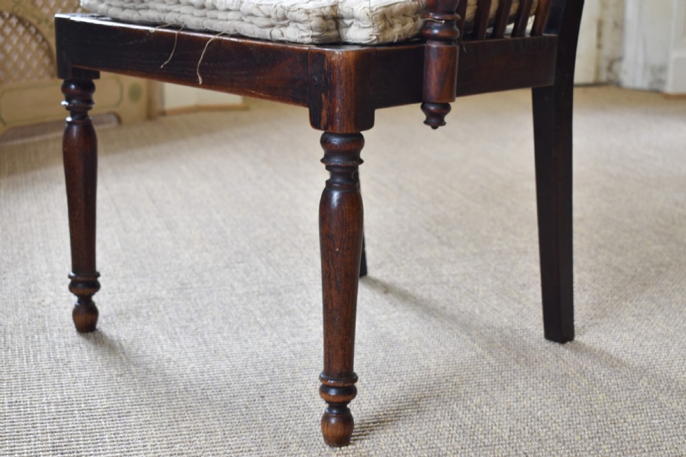 A dark timber country armchair featuring a tall spindle backrest, flat armrests on turned supports, a woven seat, and turned front legs. View V