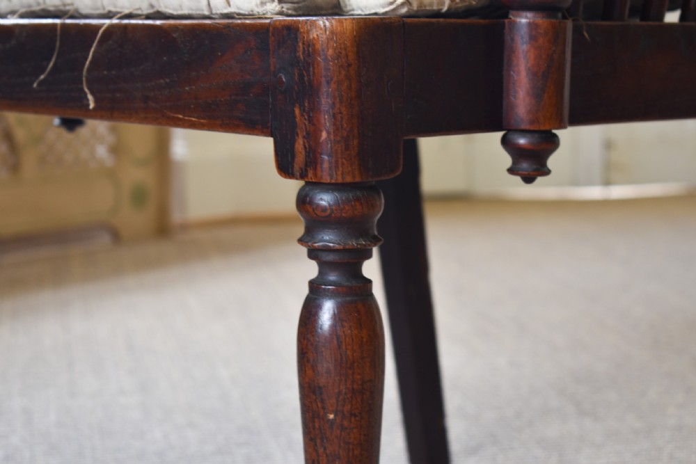 A dark timber country armchair featuring a tall spindle backrest, flat armrests on turned supports, a woven seat, and turned front legs. View VI
