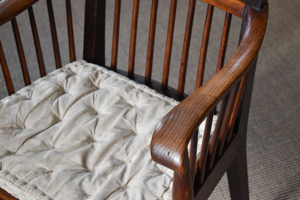 A dark timber country armchair featuring a tall spindle backrest, flat armrests on turned supports, a woven seat, and turned front legs. View VII