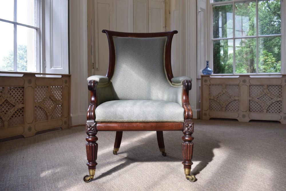 A George IV mahogany armchair with carved scroll arms, light green upholstery, and reeded turned front legs on brass castors. View II