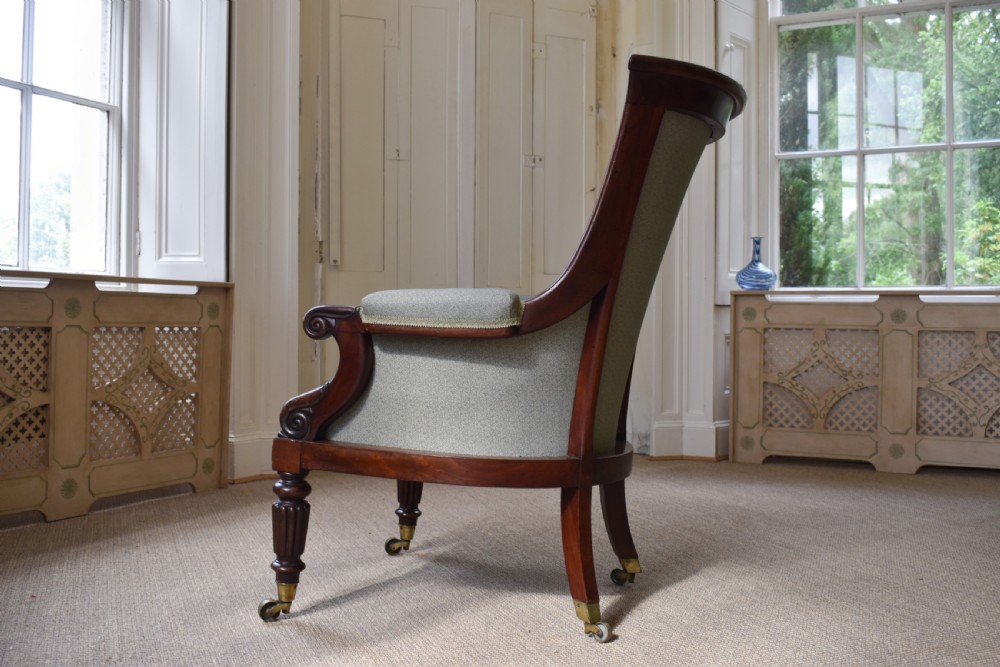 A George IV mahogany armchair with carved scroll arms, light green upholstery, and reeded turned front legs on brass castors. View III