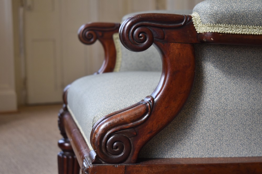 A George IV mahogany armchair with carved scroll arms, light green upholstery, and reeded turned front legs on brass castors. View IV