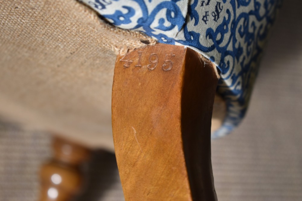 A deep-buttoned antique tub chair upholstered in a blue and white patterned fabric, set on turned timber legs with brass castors. View VI